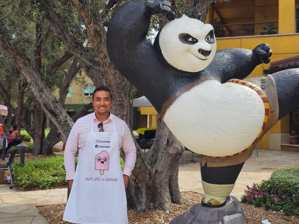 Founder of Joy on a Stick standing beside a large panda statue while wearing a branded shirt, representing the brand’s playful and joyful spirit born out of the pandemic.